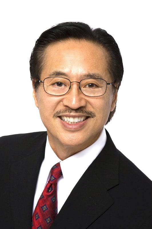 Professional man wearing glasses and a suit smiling.